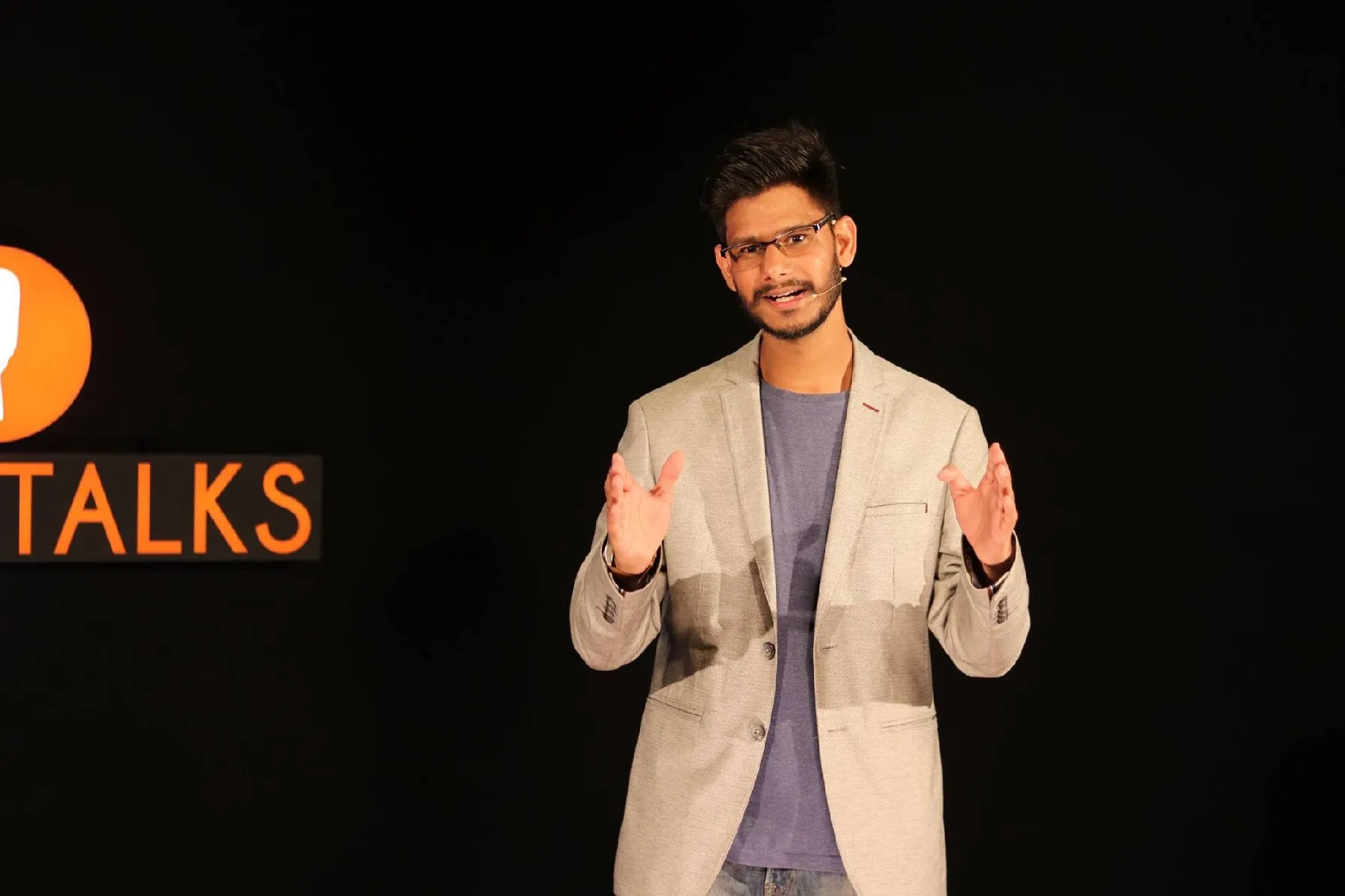 Gautam Kumawat delivering a talk under stage lighting