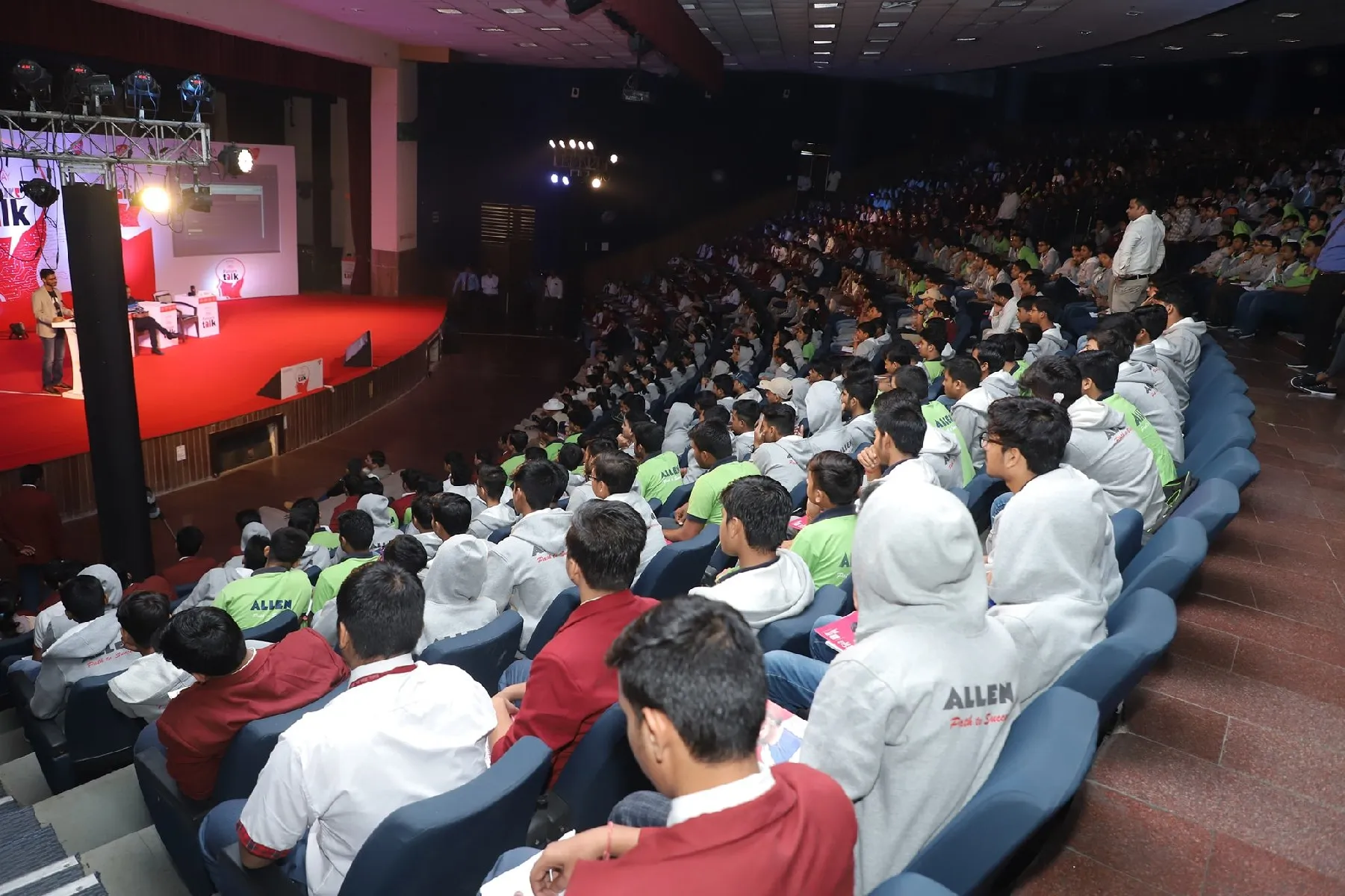 A full auditorium of students watching Gautam Kumawat speak from the stage