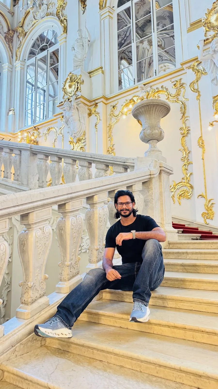 Gautam Kumawat seated on the balustraded staircase of a white and gold palace
