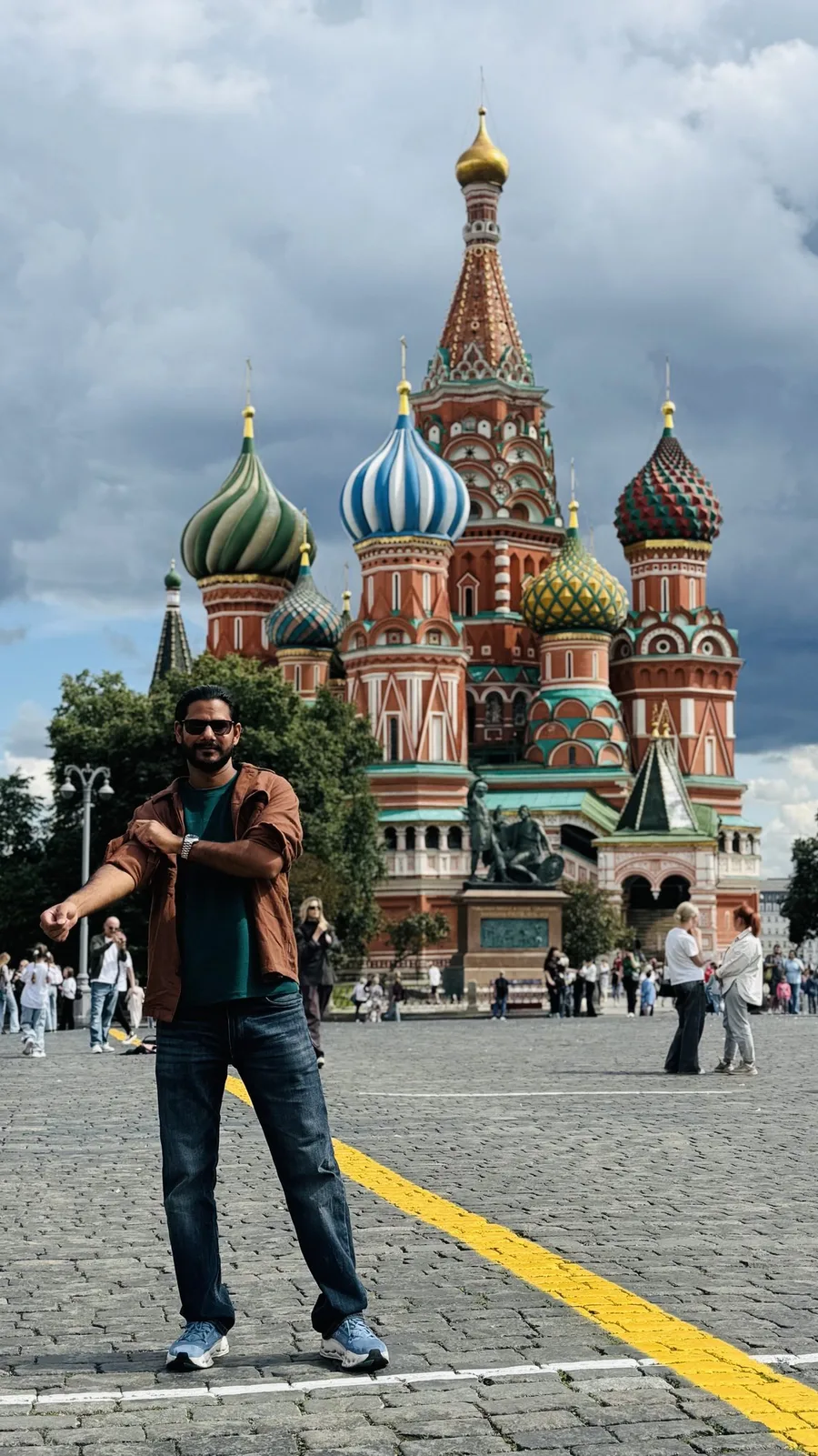 Gautam Kumawat with both arms thrown wide in front of Saint Basil's Cathedral and its painted domes