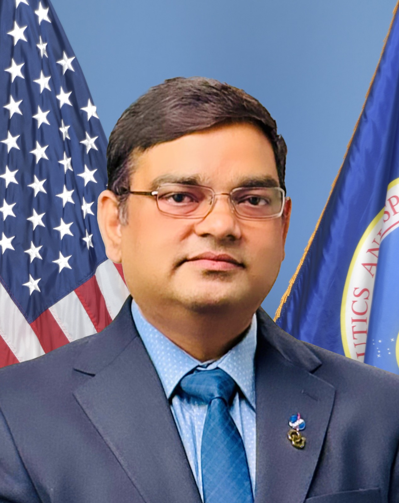 Official portrait of Ashok Prajapati in front of the United States and NASA flags